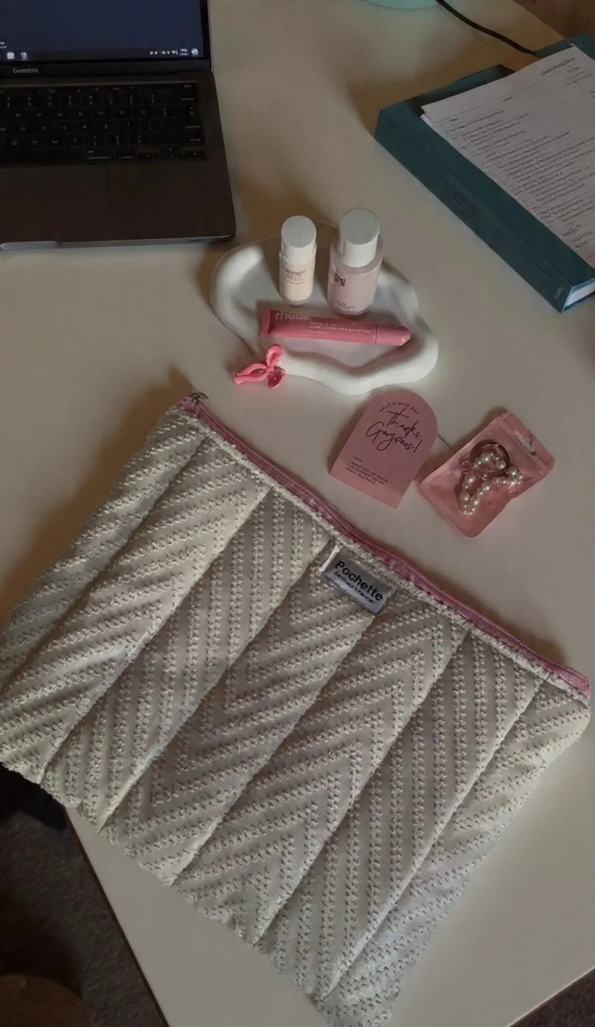 Quilted natural cotton beauty case with pink trim on desk, surrounded by cosmetic accessories