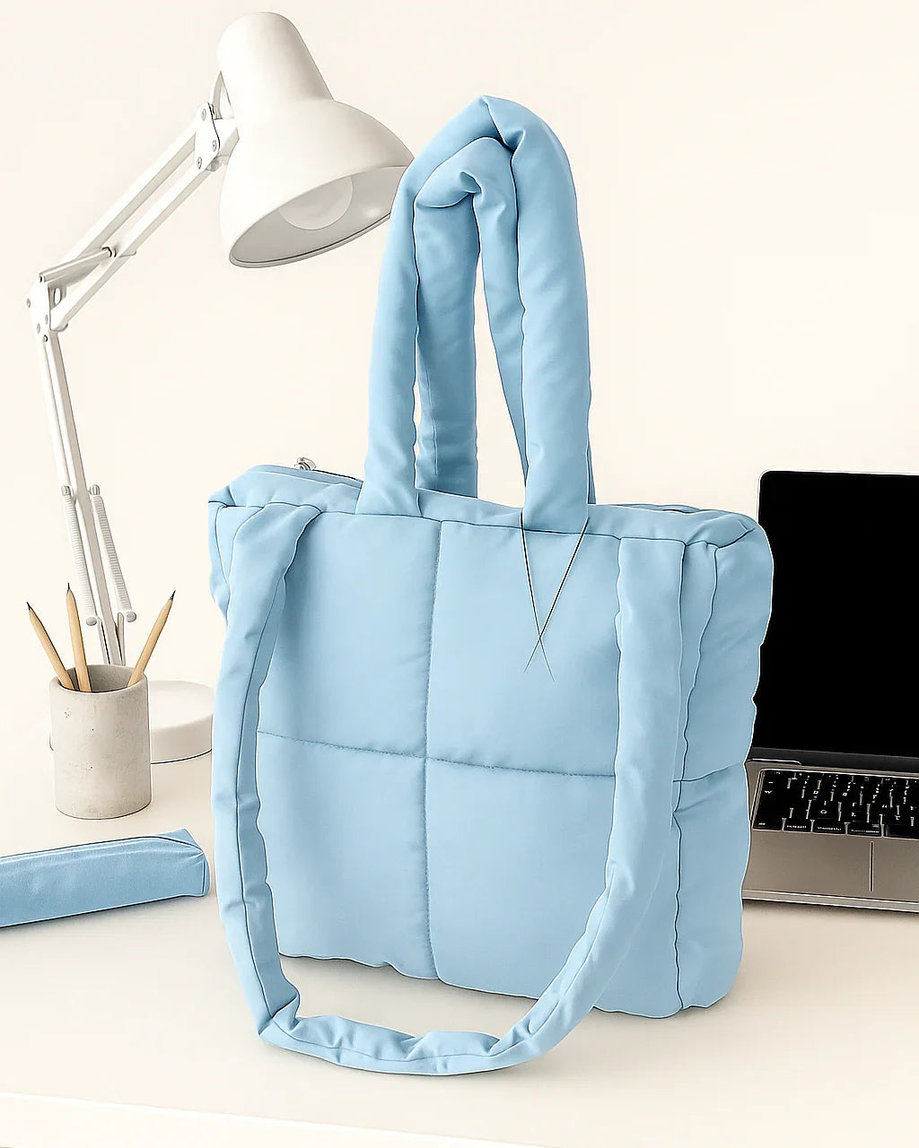 Light blue quilted cotton tote bag on a desk with a laptop and lamp