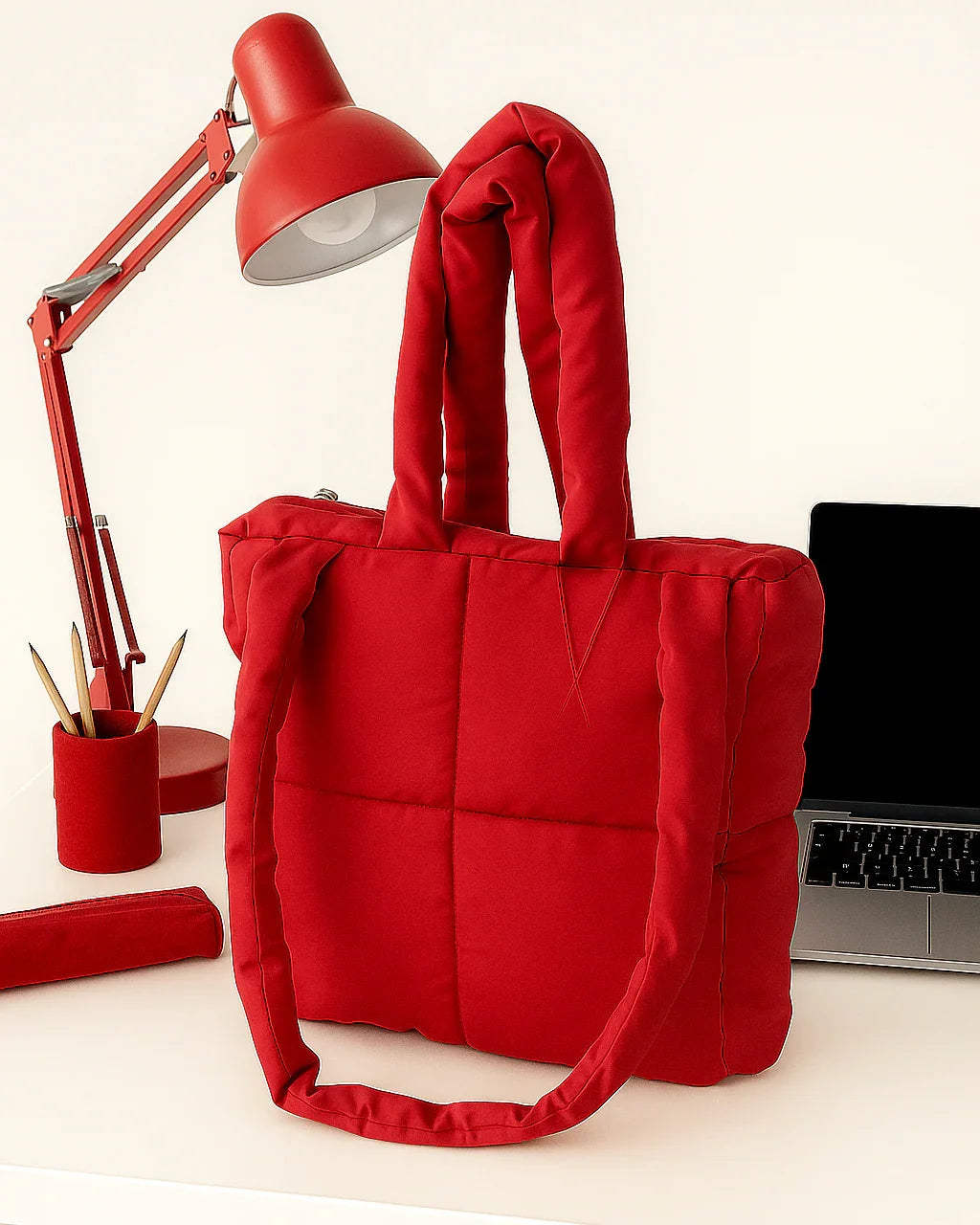 Red quilted cotton tote bag with handles on a desk next to red lamp and laptop