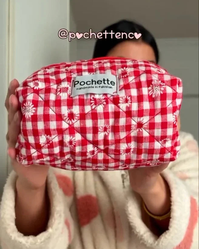 Handmade red gingham cotton beauty case with white floral pattern, held by a person