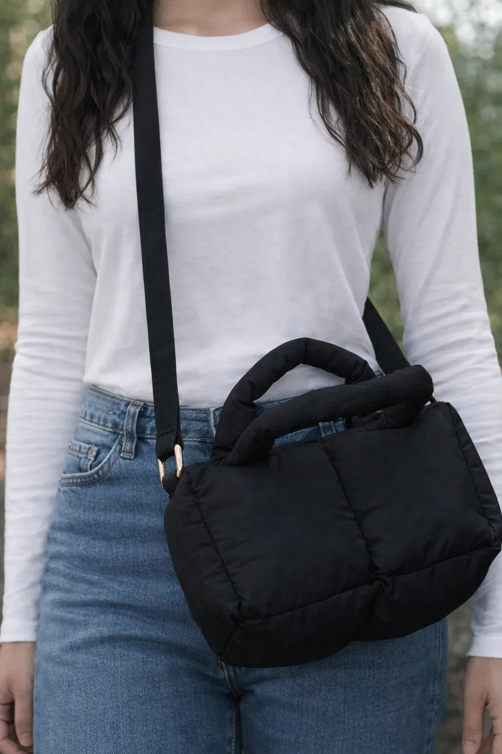 Black puffer quilted crossbody bag with handle, worn over shoulder, casual outfit