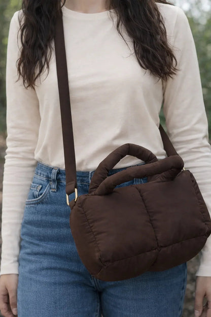 Brown quilted puffer crossbody bag with handle, worn over shoulder, casual outfit