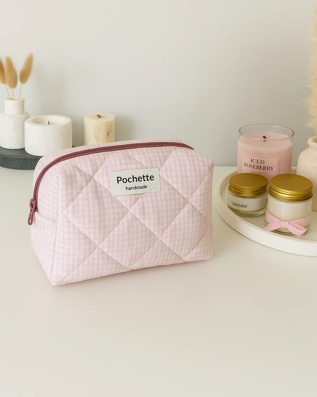 Light pink quilted cotton beauty case pouch on a table with candles and jars, minimalist decor