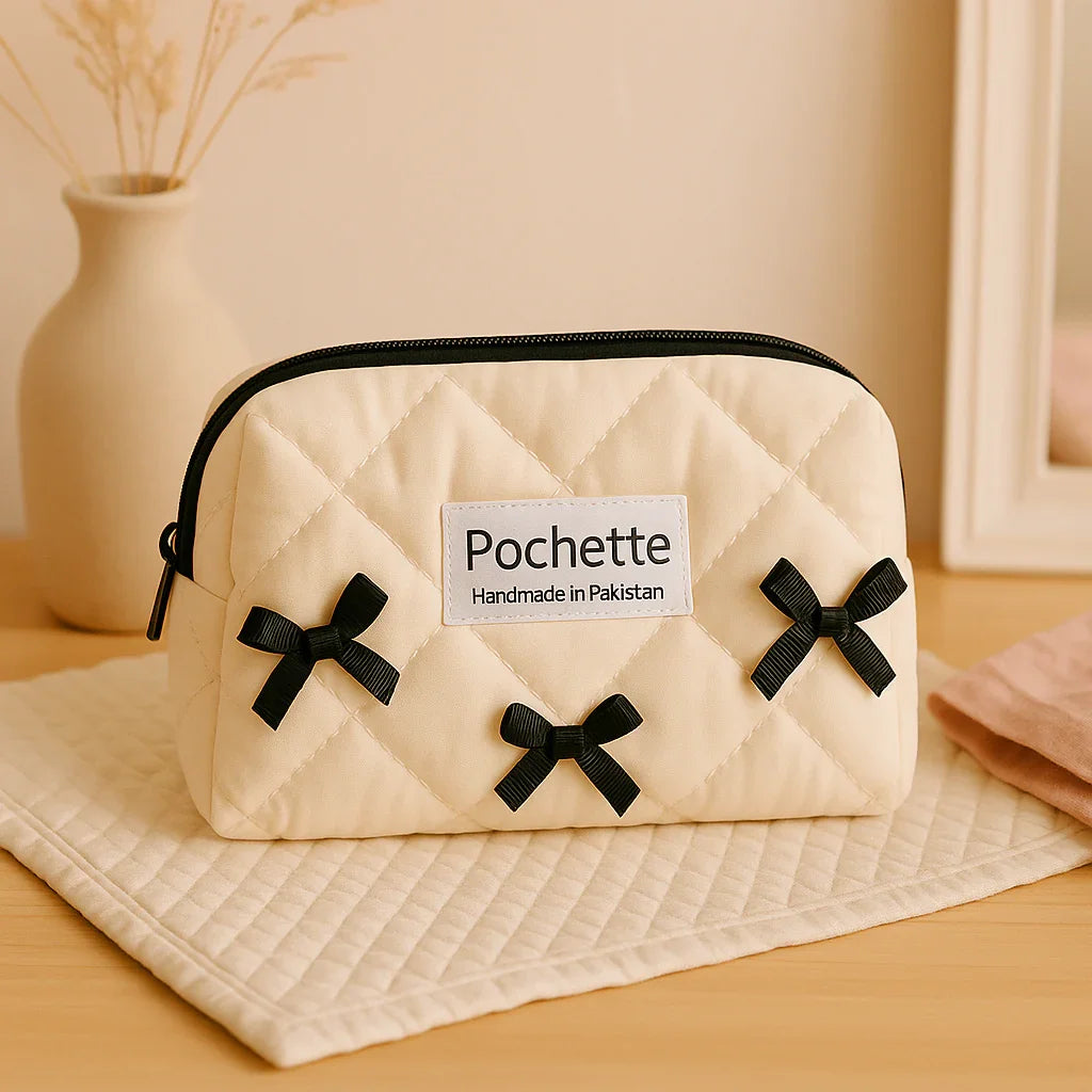 Quilted cream cotton beauty case with black bows and zipper, handmade in Pakistan.