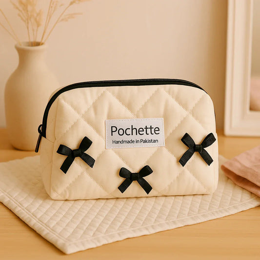 Quilted cream cotton beauty case with black bows and zipper, handmade in Pakistan.