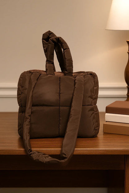Brown quilted cotton beauty case with handles, placed on a wooden desk indoors